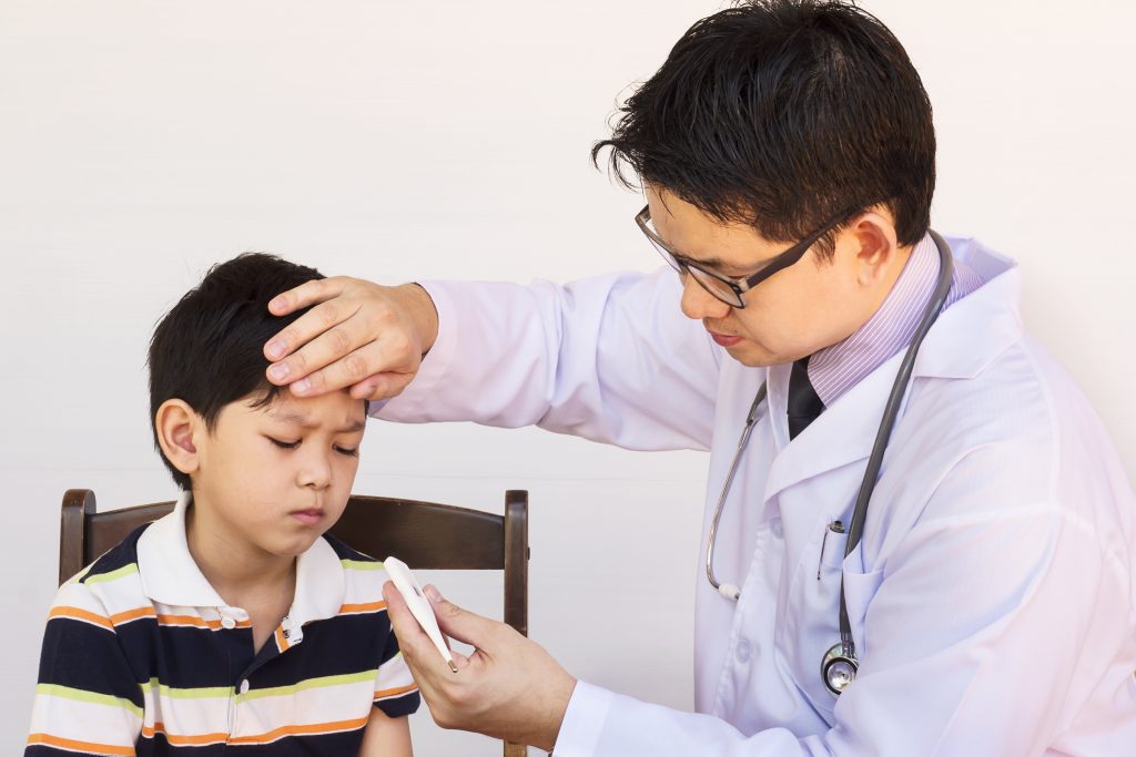 sick asian boy being examined by male doctor white background